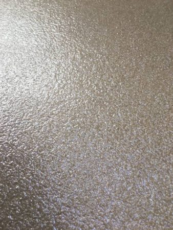 Close-up of a textured epoxy floor with a mottled appearance, showcasing shades of gray with a subtle glossy sheen reflecting ambient light.