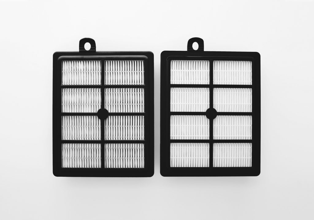 Two identical square-shaped, black-framed HEPA filters are presented side by side against a white background. Each filter features a symmetrical grid design with white pleated filter media, indicating they are clean and unused. The simple, minimalist presentation emphasizes the filters' functionality and cleanliness.