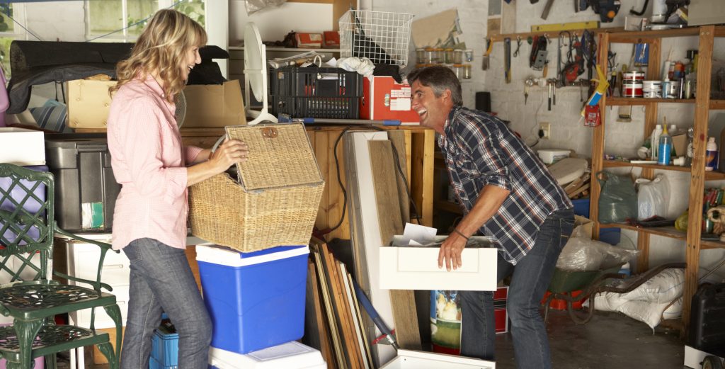 A happy couple working on organizing a messy garage.