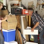 A happy couple working on organizing a messy garage.