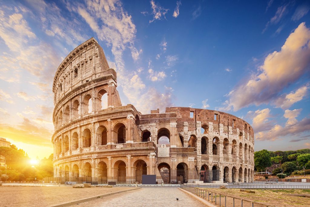 The Colosseum in Rome, with its ancient arched concrete exterior, under a dramatic sky at sunset, capturing the historic grandeur of this iconic amphitheater.