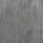 Close-up of vertical streaks and water droplets on a concrete, showing moisture on the material.