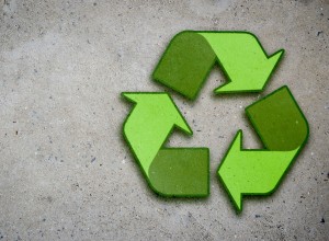 A vibrant green recycling symbol composed of three chasing arrows on a rough concrete surface, representing the concept of sustainability and environmental conservation of concrete and recycled aggregates. Preserve your concrete with an epoxy coating.