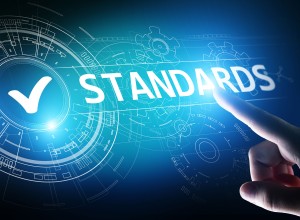 Close-up of a hand pointing toward the word "STANDARDS" on a digital interface with futuristic blue HUD (heads-up display) elements, including gears and circuit-like graphics. A large white checkmark is shown inside a glowing circle, symbolizing approval or compliance.