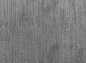 Close-up of vertical streaks and water droplets on a concrete, showing moisture on the material.