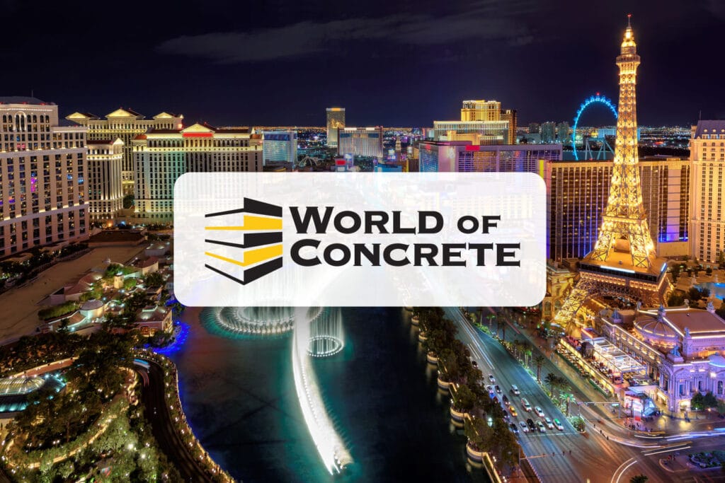 Aerial night view of the Las Vegas Strip, prominently featuring the brightly lit replica of the Eiffel Tower at the Paris Las Vegas Hotel. The bustling street is lined with illuminated hotels and the Bellagio fountain show is visible. Overlaying the image is the 'World of Concrete' logo with stylized black and yellow stripes, suggesting a connection to the construction industry event.