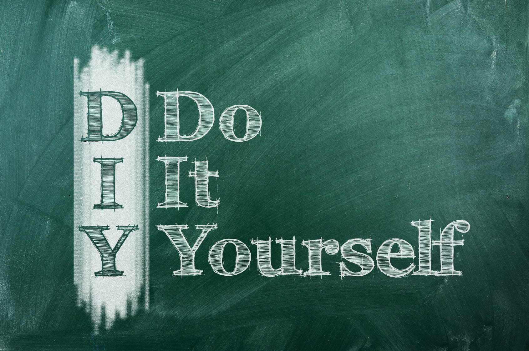 The acronym 'DIY' which stands for 'Do It Yourself,' is written in large white chalk letters on a dark green chalkboard. The first letters of each word are vertically aligned to form the acronym 'DIY' with the rest of the words written to the right, creating an instructional or motivational message often associated with crafting or home improvement projects.