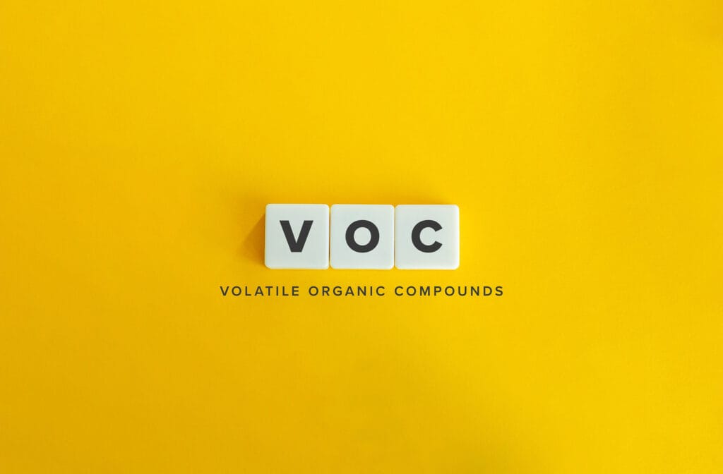 A minimalistic image with the letters 'VOC' displayed on three white square tiles against a bright yellow background. Below the tiles, the text 'Volatile Organic Compounds' is written in black, centered beneath the letters.