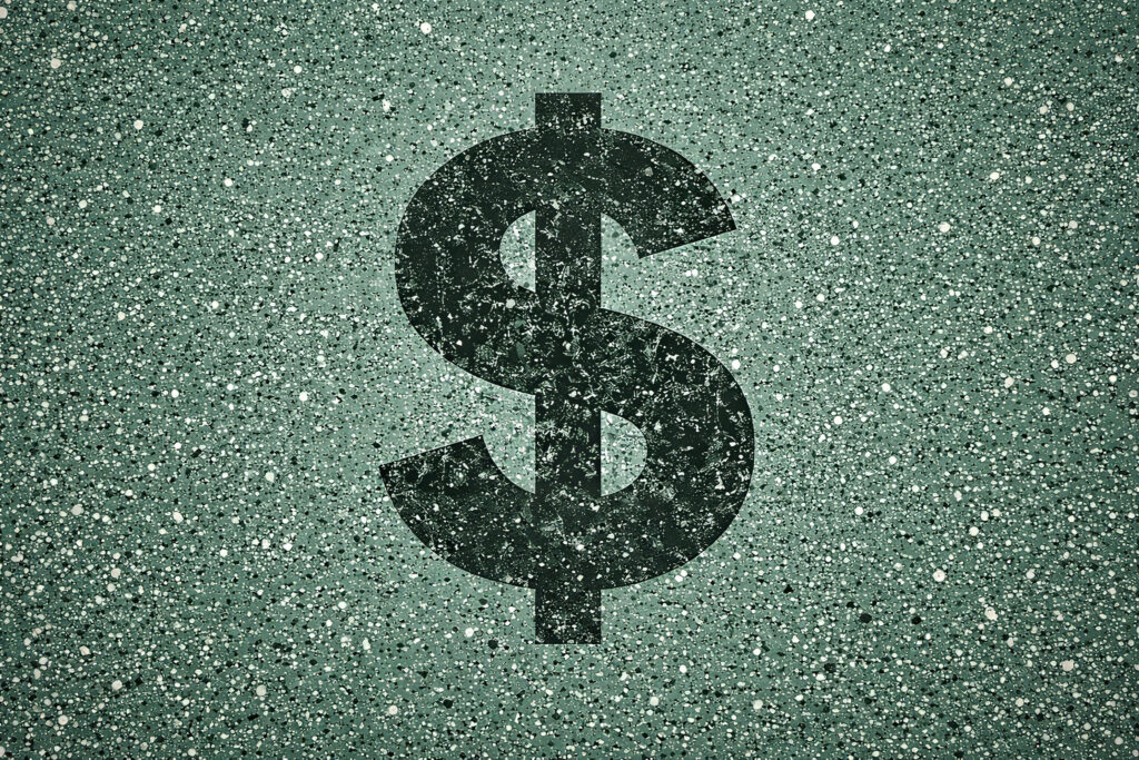 Overhead view of a green epoxy garage floor with a speckled finish, featuring a large, distressed dark green dollar sign painted at the center.